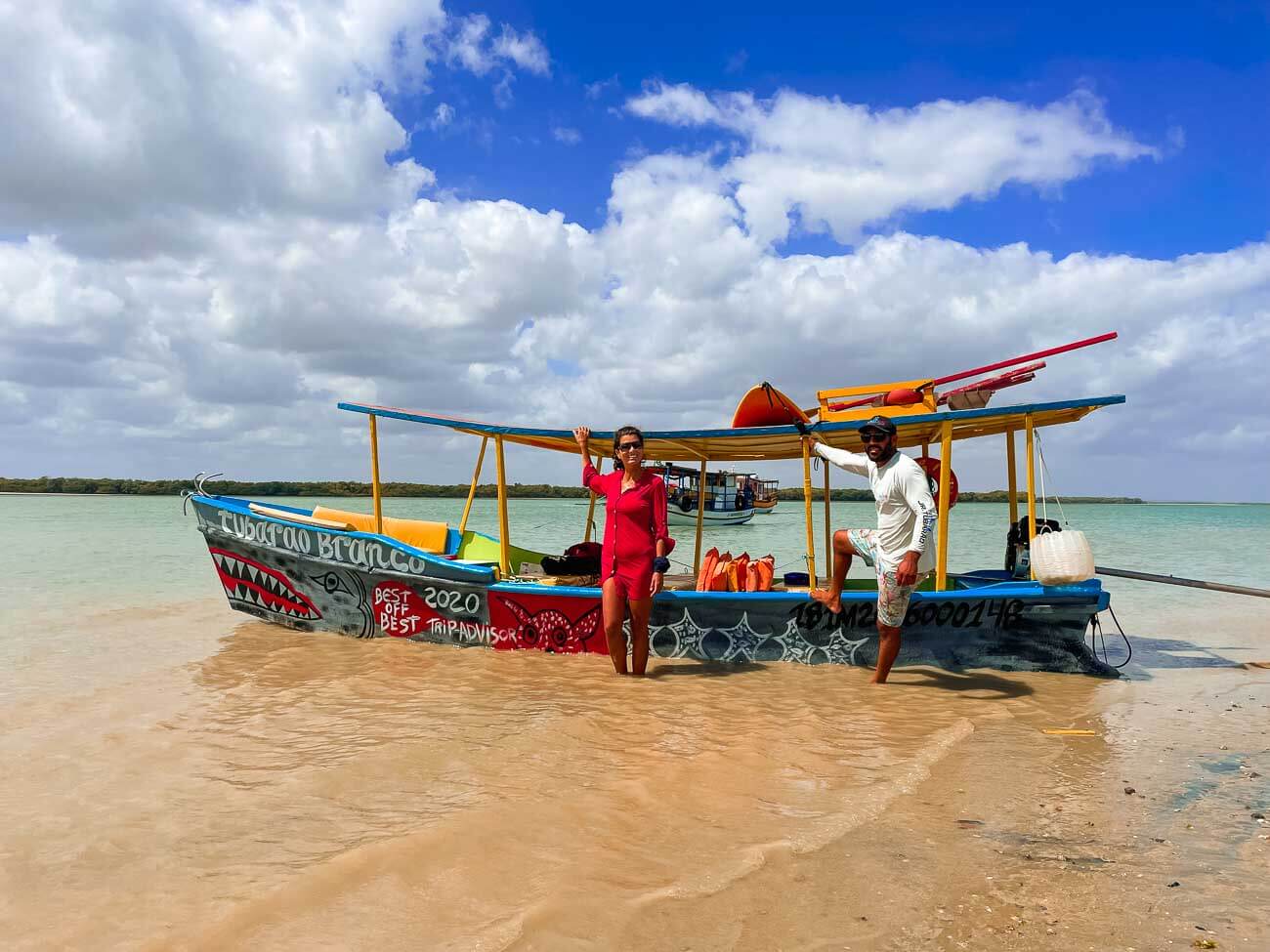 Uma mulher de vestido vermelho encostada em um barco em Galinhos