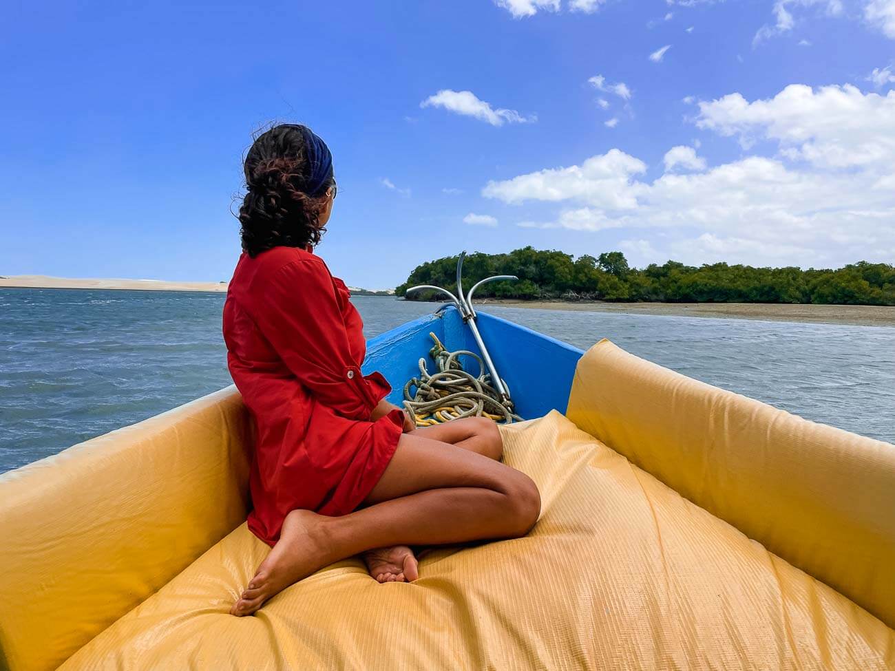 Mulher sentada na ponta de um barco em meio ao rio de Galinhos