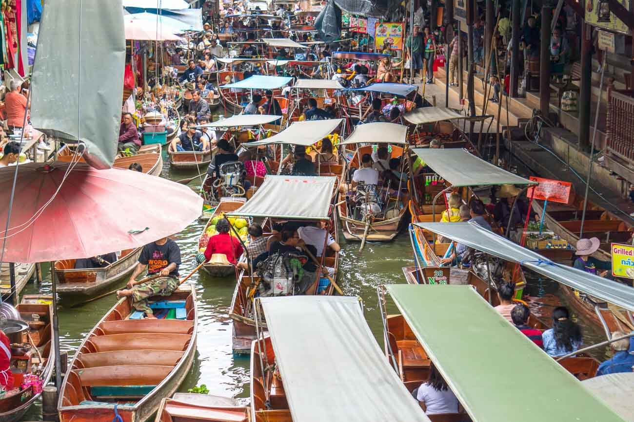 Barcos coloridos lotados de pessoas e mercadorias no mercado flutuante de Damnoen Saduak, em Bangkok.