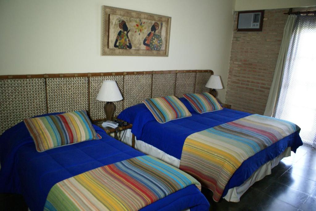 Quarto de hotel com uma cama de solteiro e uma de casal com móveis rústicos.