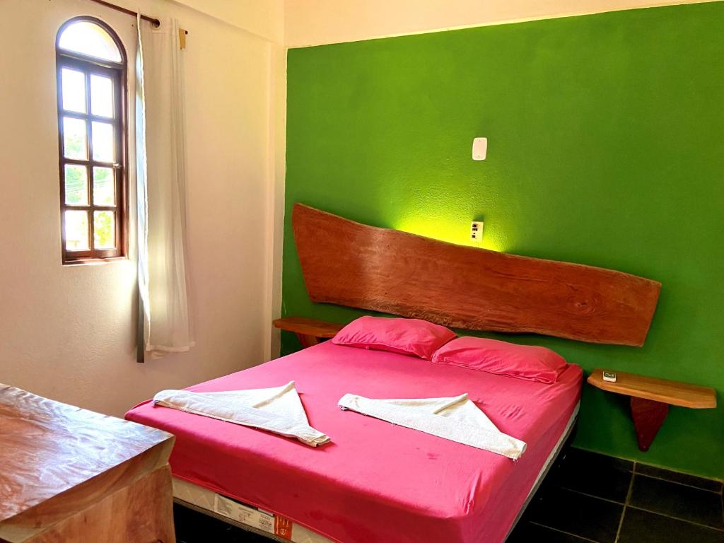 Cama de casal em hostel em Cumuruxatiba e uma parede pintada na cor verde folha.