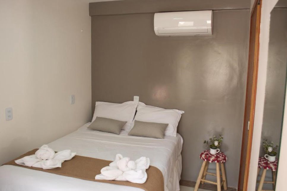 Cama de casal com cores em tons de branco, cinza e bege.