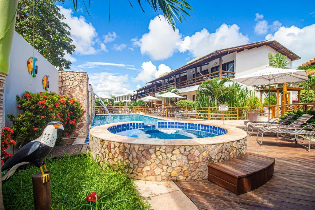 Piscina ao ar livre em pousada em Jericoacoara com áreas verdes e deck com espreguiçadeiras.