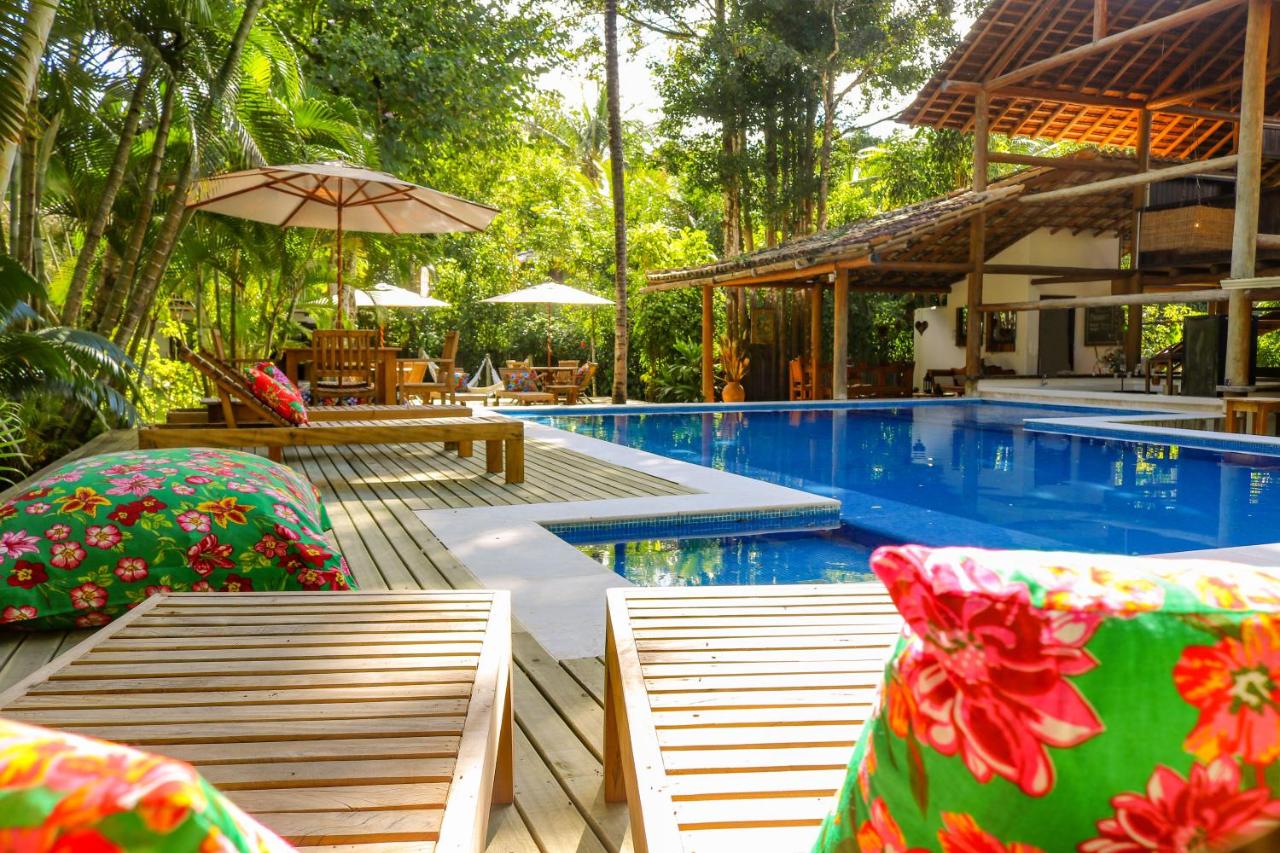 Piscina ao ar livre com espreguiçadeiras em deck de madeira e muita natureza ao redor.