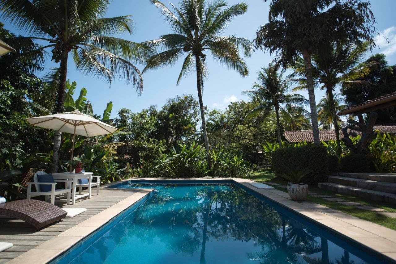 Piscina grande ao ar livre com mesas e cadeiras com guarda-sóis e espreguiçadeiras.