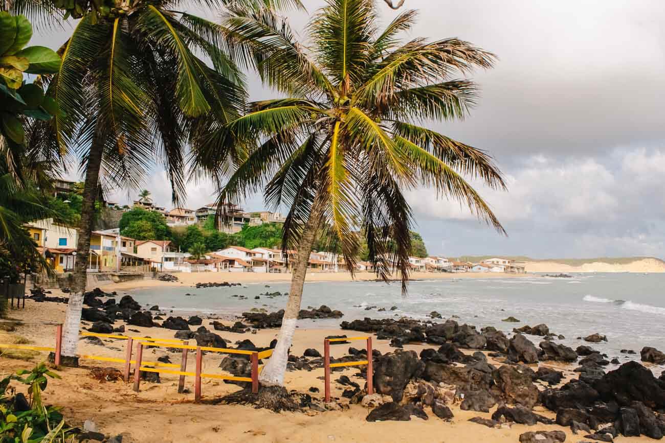 Praia da Cacimba em Baía Formosa com pedras na areia e o mar tranquilo em um dia nublado.