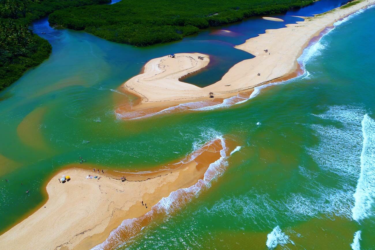 Vista de cima da Praia de Cumuruxatiba se encontrando com o rio