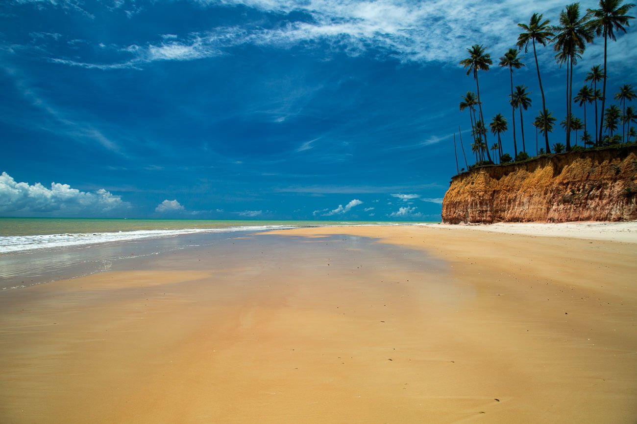Faixa de areia larga e extensa da Praia BArra do Cahy e falésias repletas de coqueiros