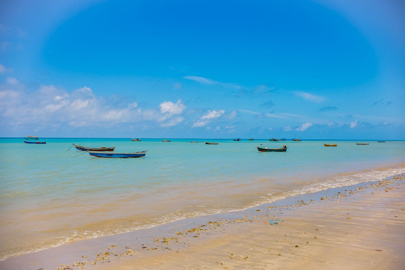 Mar calmo e cristalino da Praia de Cumuruxatiba com barcos de pescadores