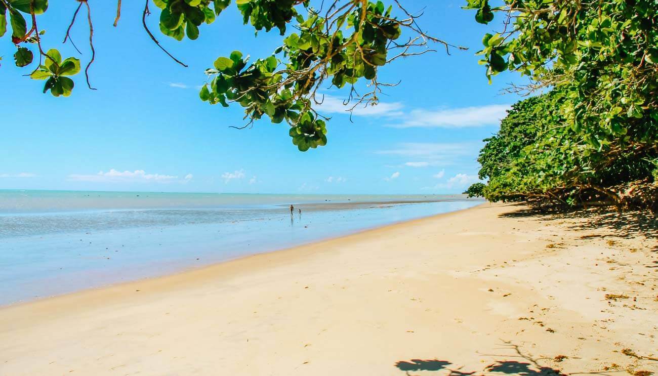 Um homem e um menino caminhando na areia vazia da Praia de Peixe Grande