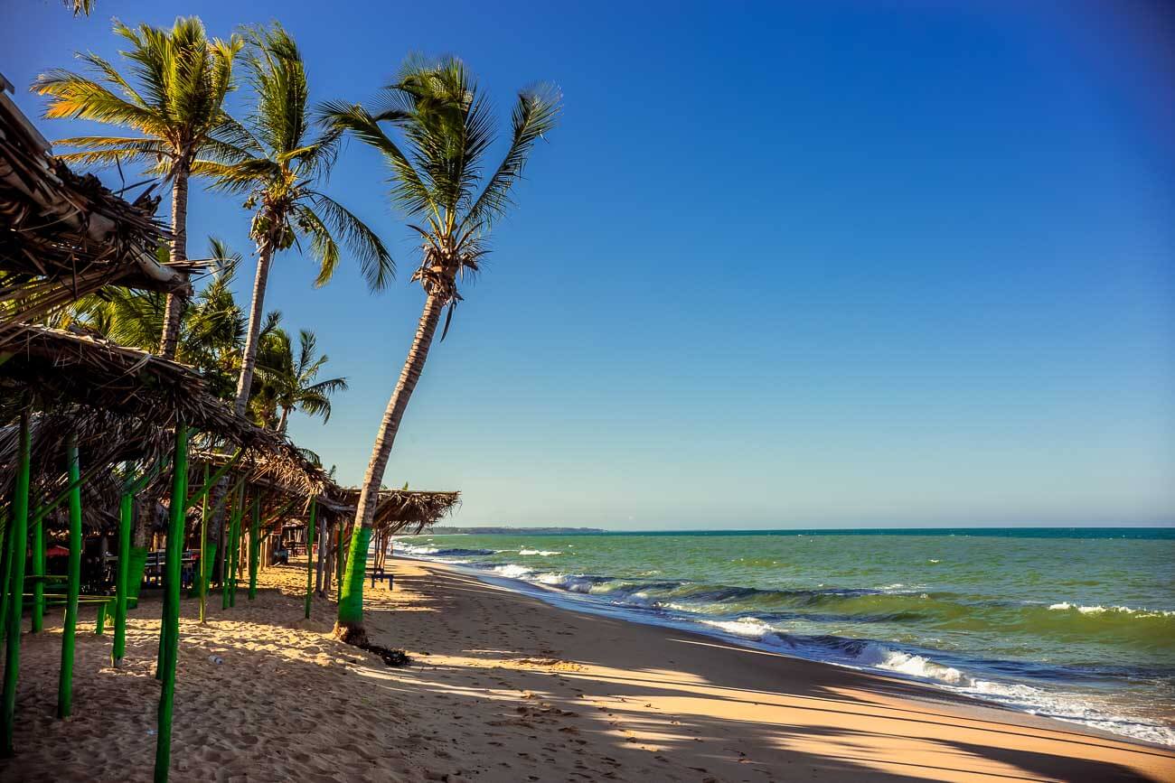 Vista de uma parte da Praia Novo Prado com coqueiros na orla e quiosques