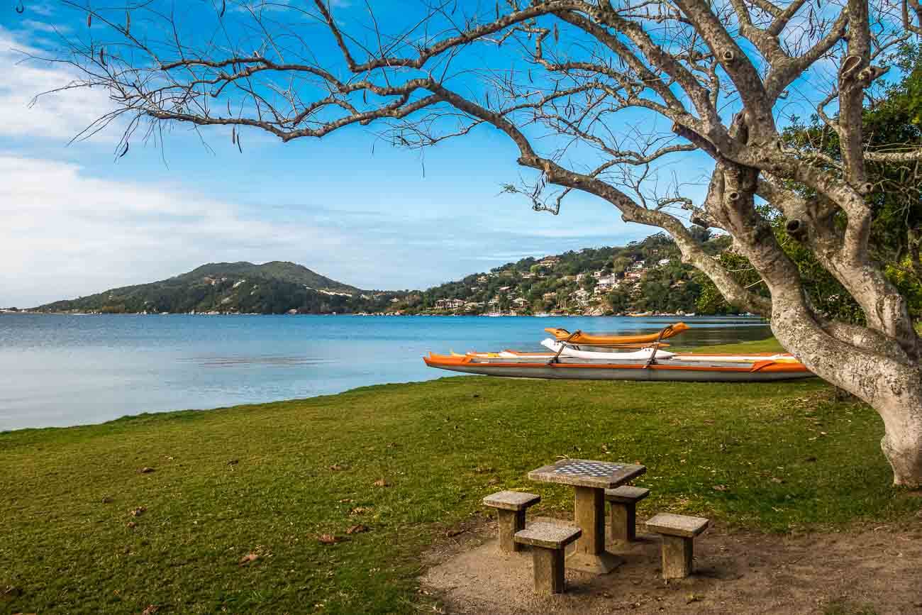 Área gramada da Lagoa da Conceção com alguns botes e uma mesa de xadrez.