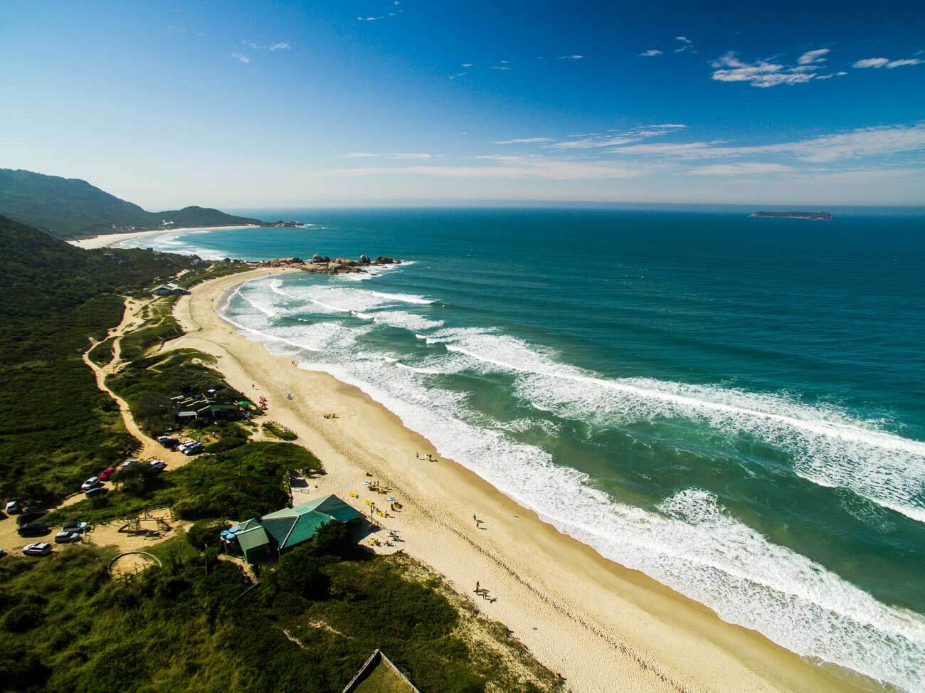 Vista aérea da Praia Mole em Florianópolis com o mar agitado cheio de ondas e faixa de areia vazia