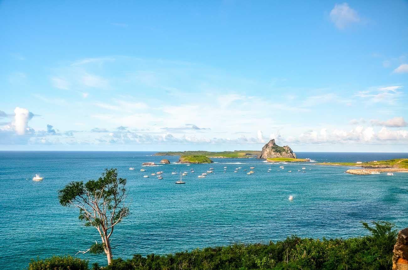 Vista panorâmica e de longe do Porto de Santo Antônio em Fernando de Noronha com barcos no mar.