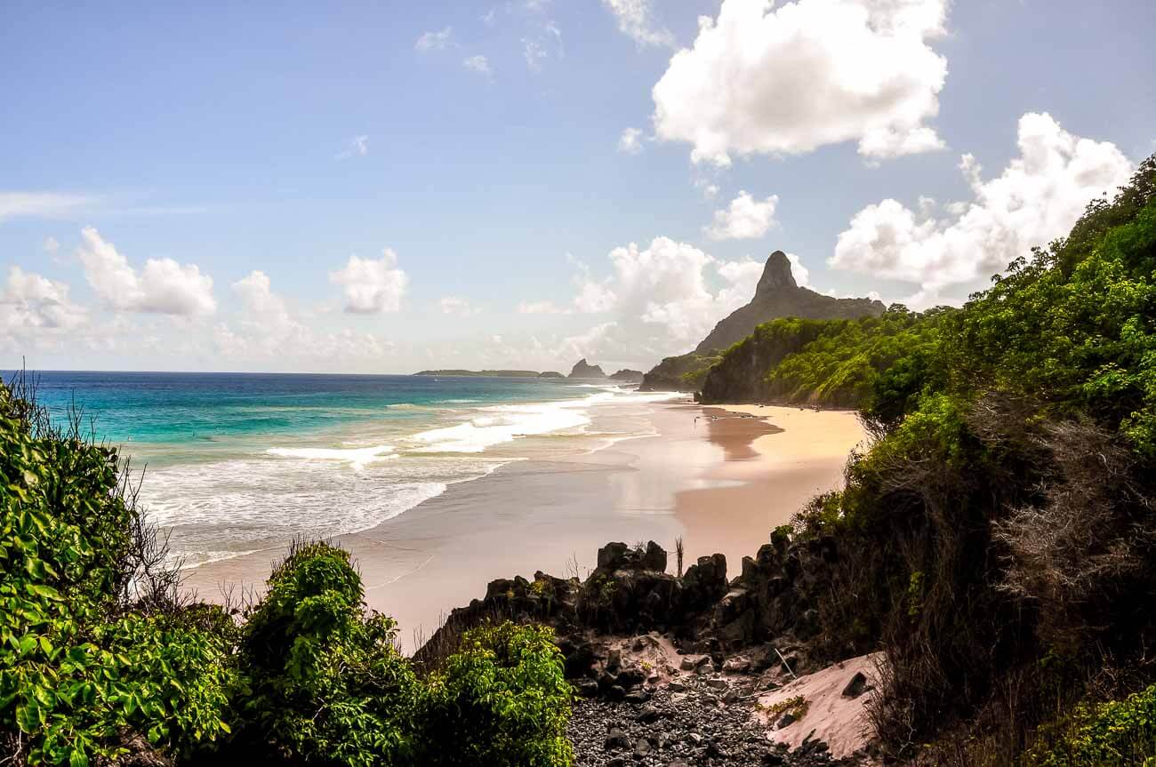 Faixa de areia larga da Praia do Bode cercada por natureza e vista para montanhas.