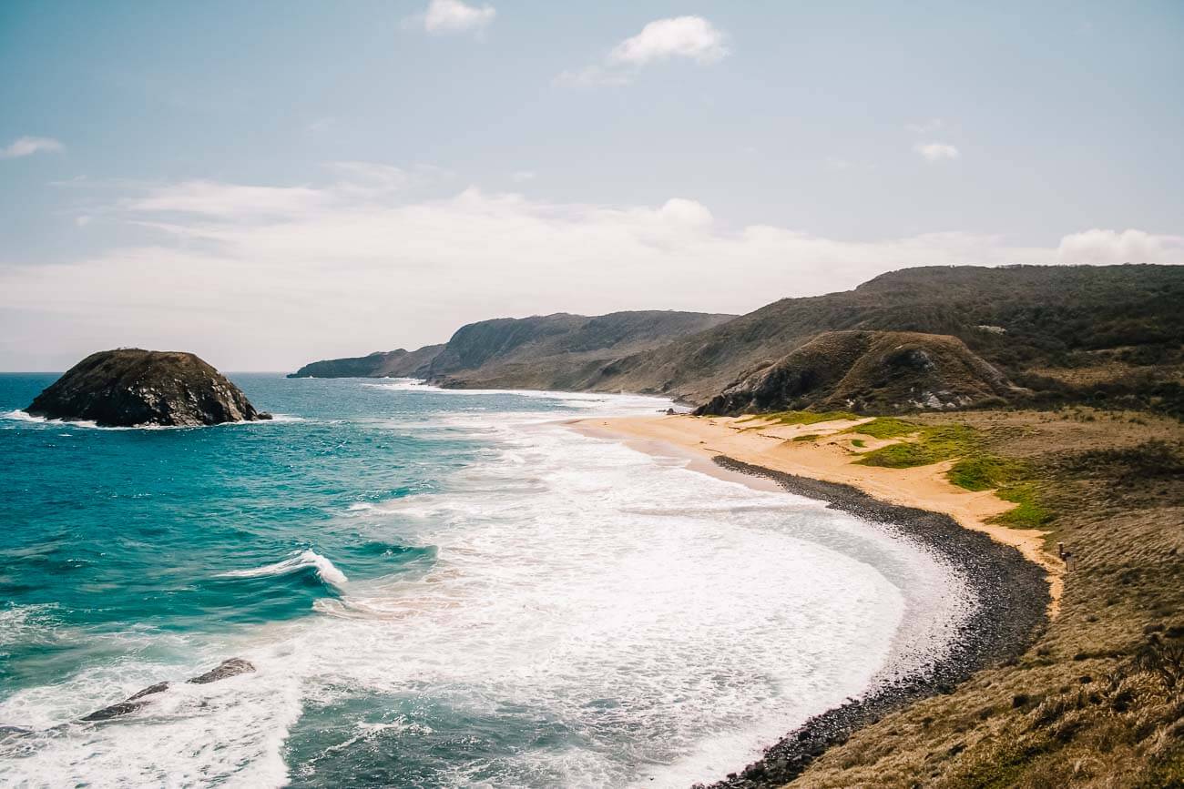 Vista do alto da Praia do Leão, com a areia vazia e mar agitado.