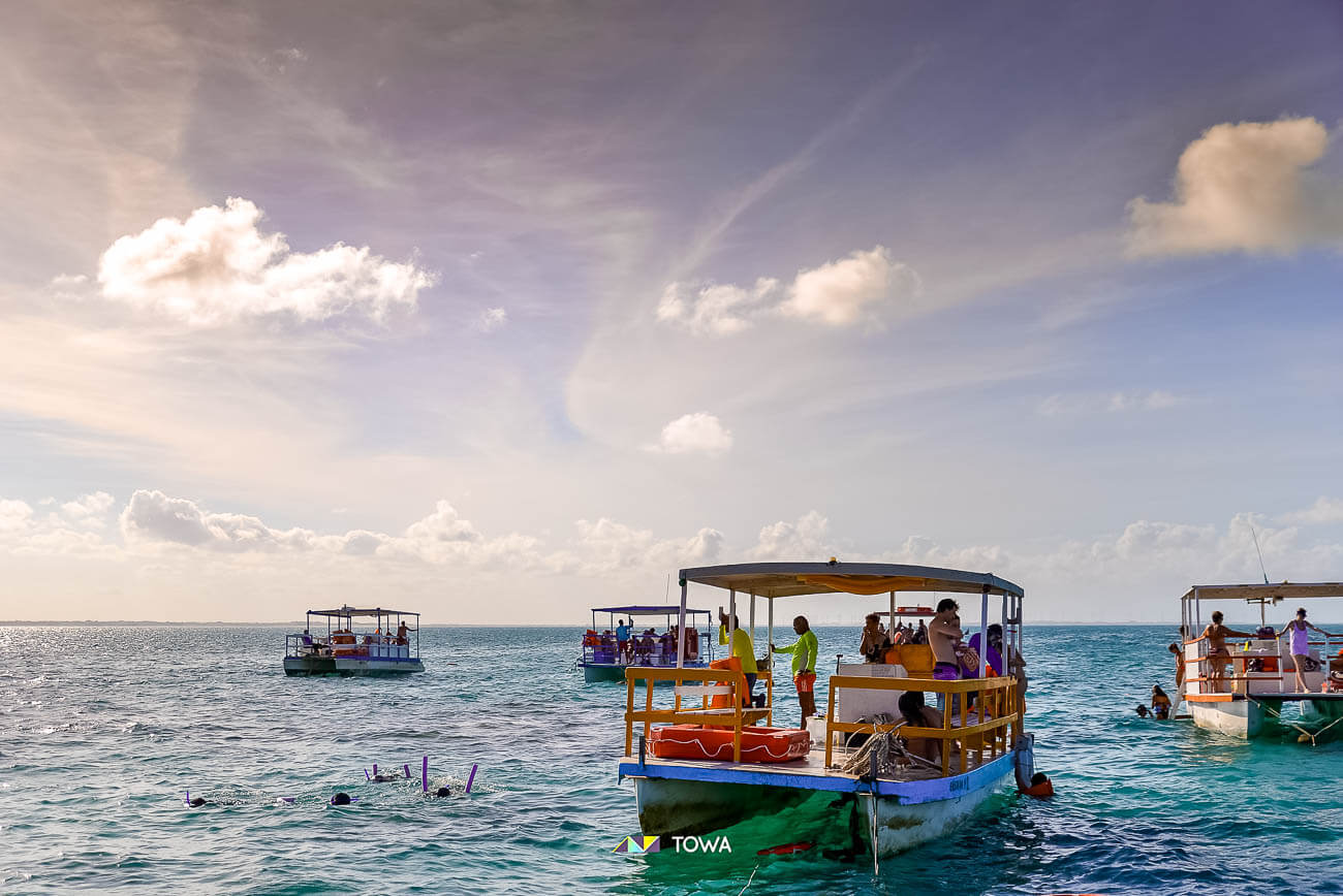 Jangadas coloridas nos Parrachos de Maracajaú com pessoas praticando snorkel
