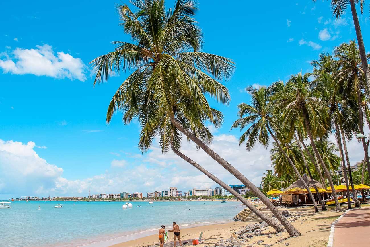 Praia da Pajuçara em Maceió, com águas cristalinas e a cidade ao fundo.