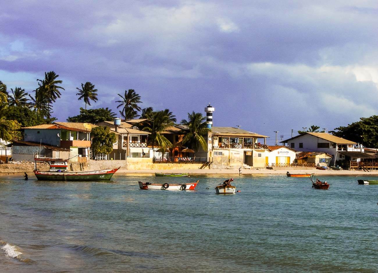 Pontal do Coruripe em Alagoas com barcos de pescadores e casinhas ao fundo.