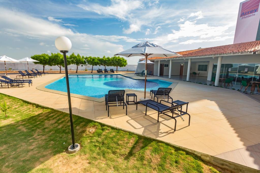 Piscina ao ar livre com espreguiçadeiras e guarda-sóis em hotel em Parnaíba.