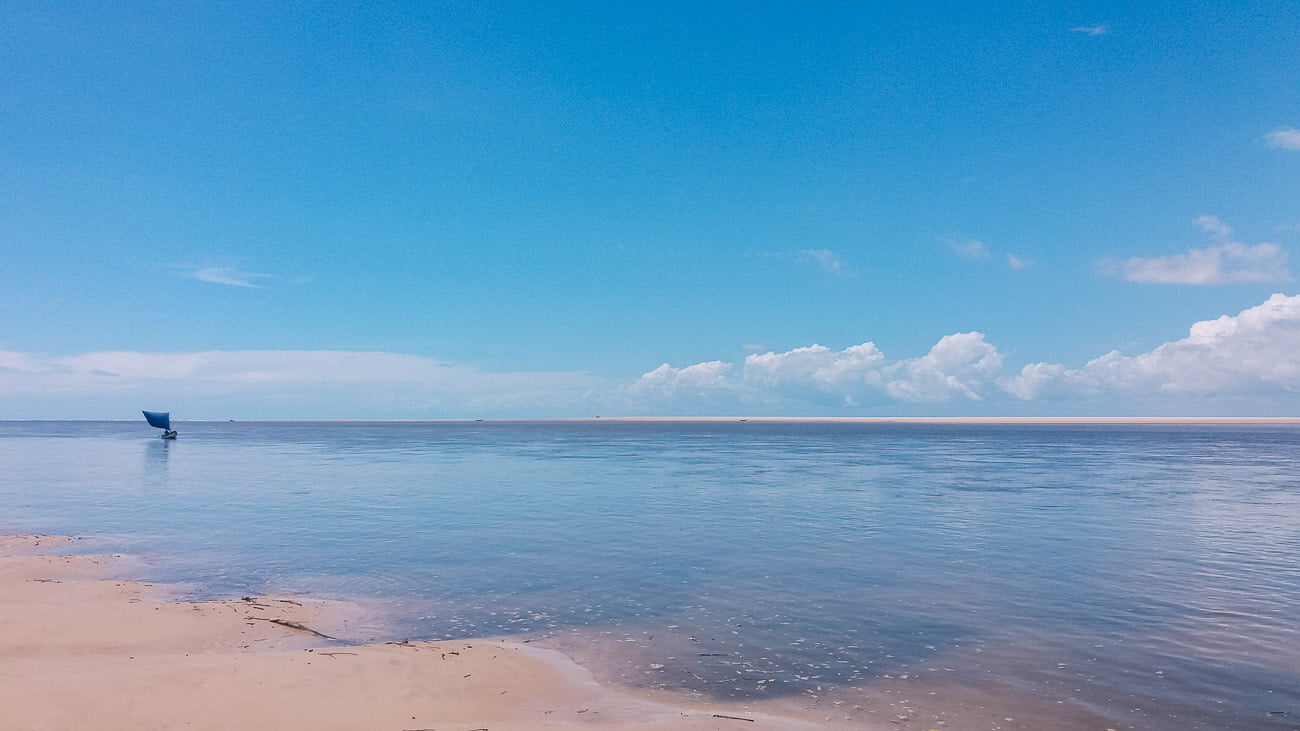 Vista de lagoa na Ilha das Canárias no Delta do Parnaíba com um barco ao fundo.