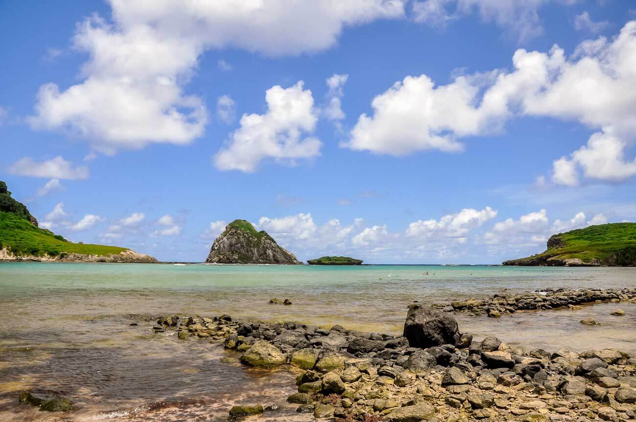 Mar cristalino em tons azuis esverdeados da Praia da Atalaia com formações de pedras.