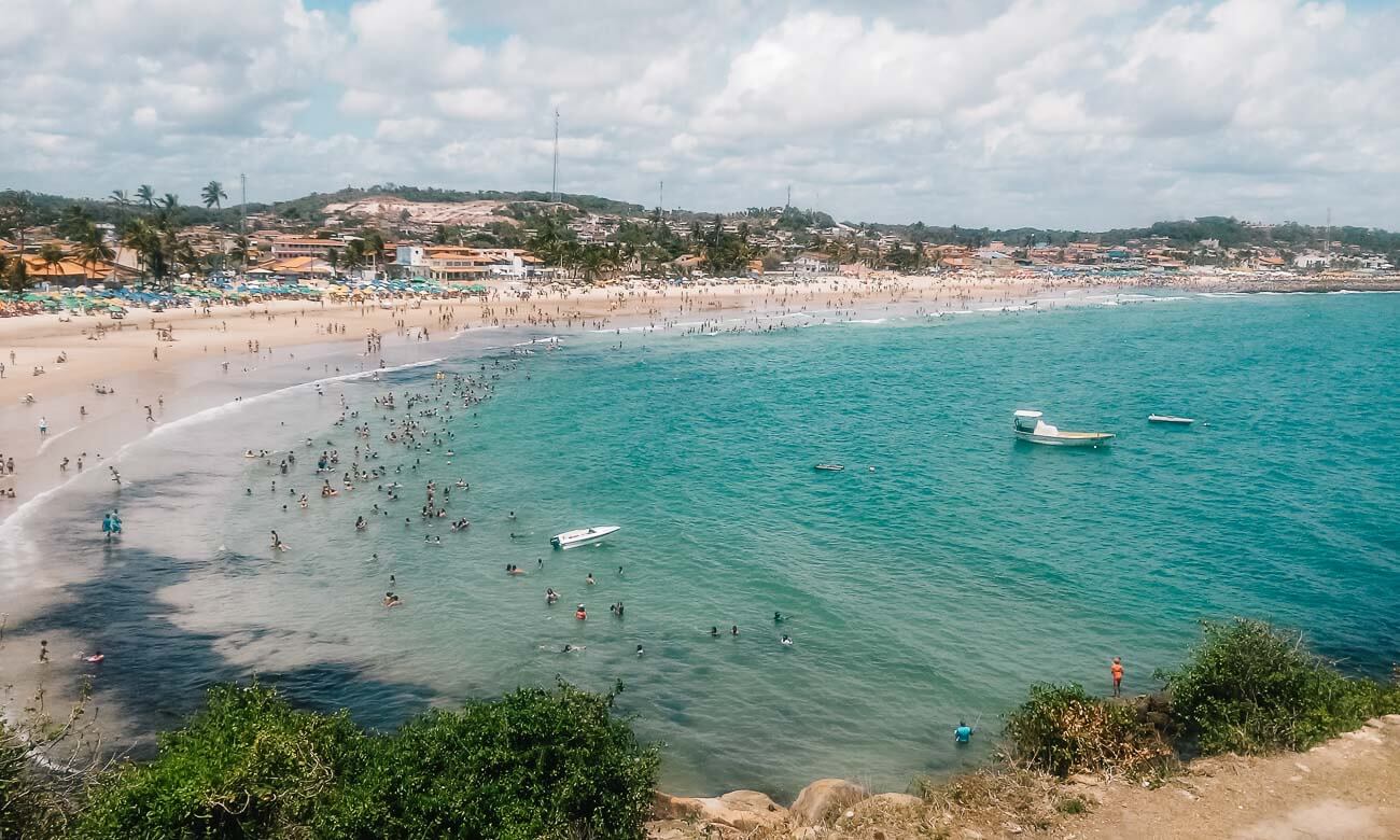 Vista de cima da Praia de Gaibú em um dia lotado, com o mar repleto de banhistas.