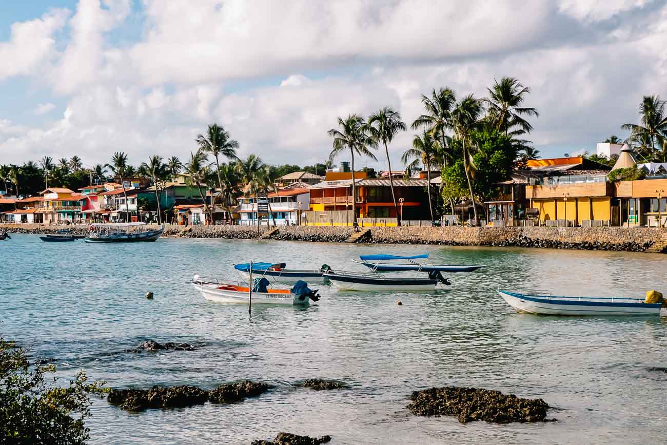 Uma lagoa com barcos de pescadores e ao fundo uma vila em Morro de São Paulo.