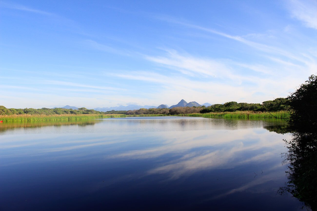 Vista da Lagoa de Itapebussus com águas escuras e cercada por natureza.