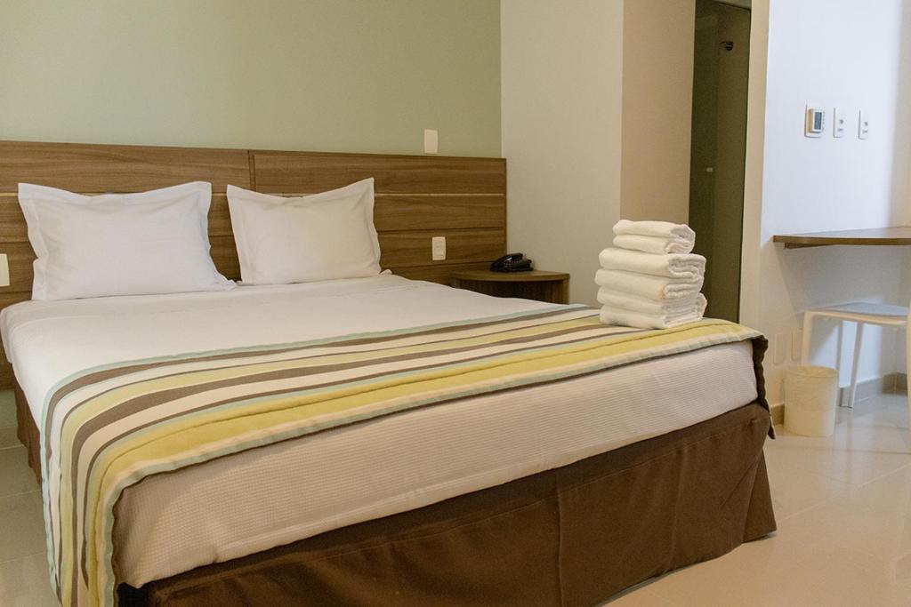Cama de casal com cabeceira de madeira e toalhas brancas em cima.