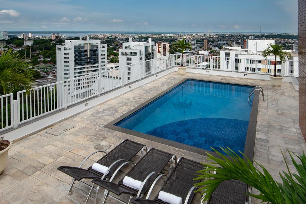 Piscina ao ar livre com espreguiçadeiras, ficando no terraço de um hotel com vista para a cidade de Manaus.