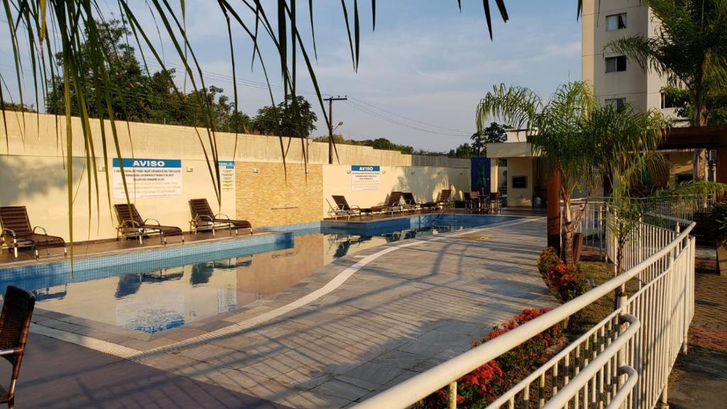 Piscina ao ar livre com espreguiçadeiras do lado esquerdo. Há um canteiro com flores e plantas próximo à piscina.
