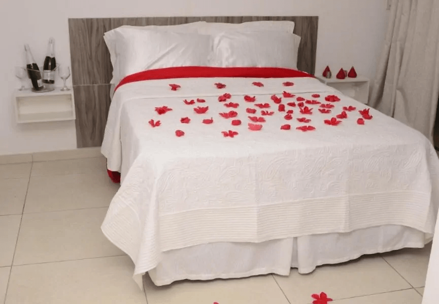 Cama de casal com pétalas de rosas em cima.