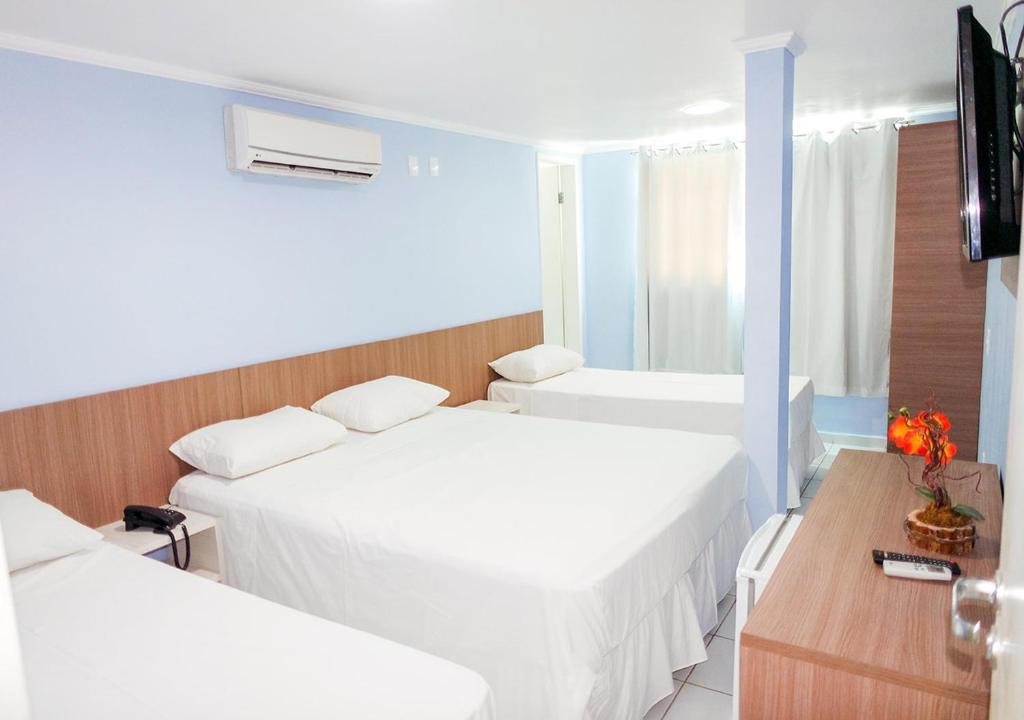 Camas com lençóis brancos em quarto de pousada em João Pessoa.