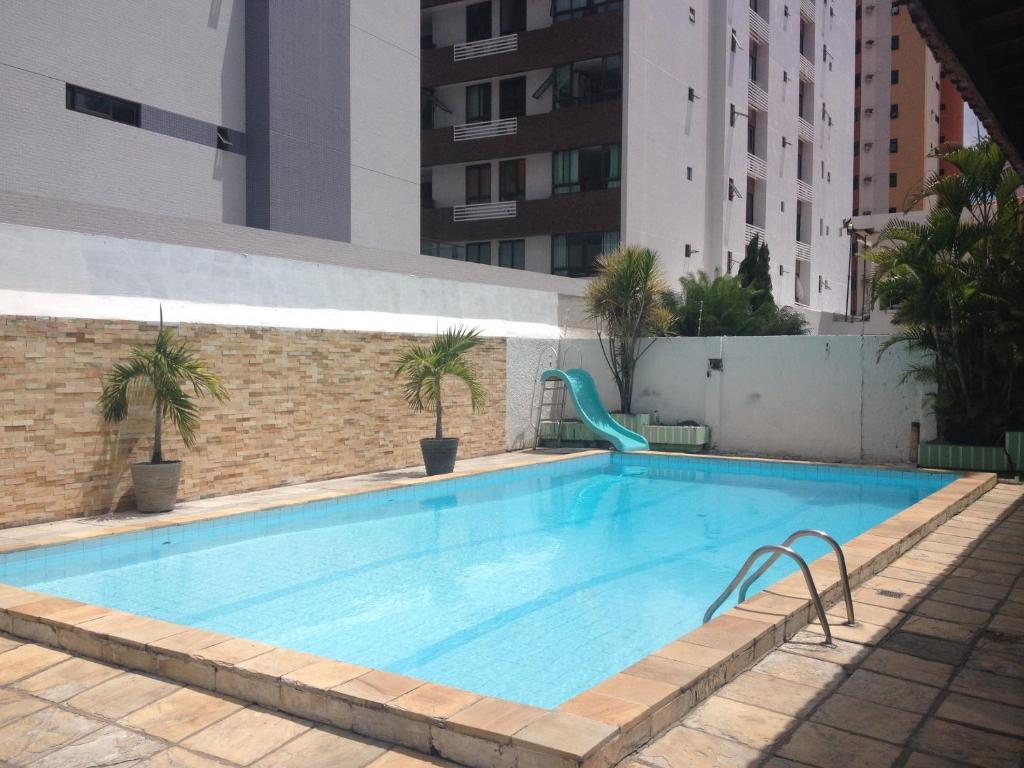 Piscina ao ar livre com dois vasos de plantas na borda e um escorrega.