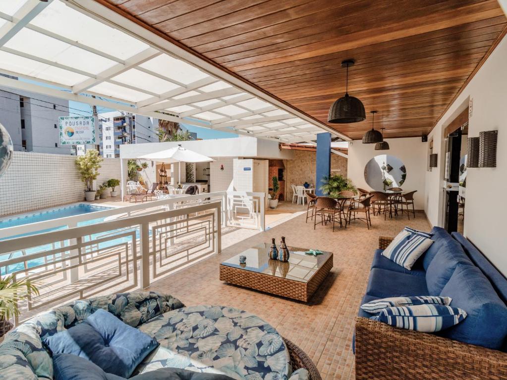 Lounge com sofás, poltronas e piscina ao ar livre em pousada em João Pessoa