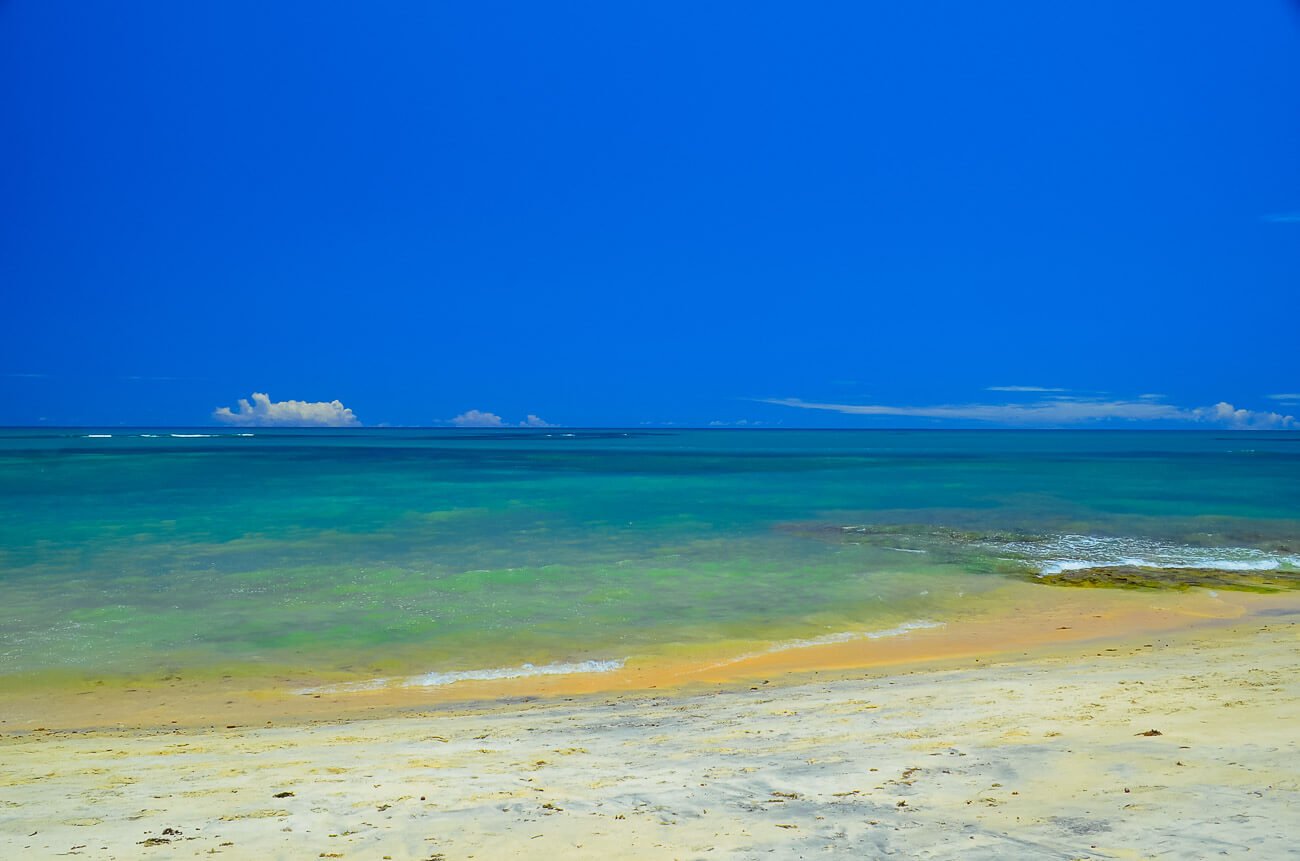 Praia em Arraial d'Ajuda com águas azuis cristalinas e sem ondas.