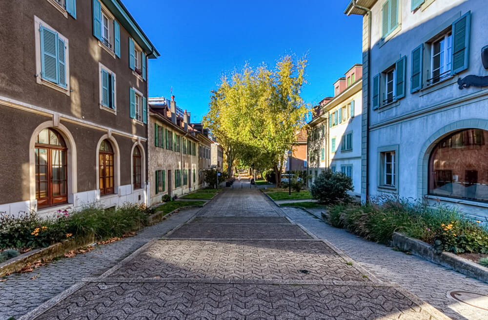 Rua no bairro de Carouge, em Genebra. Há prédios nas laterais e uma ruazinha calçada ao meio.
