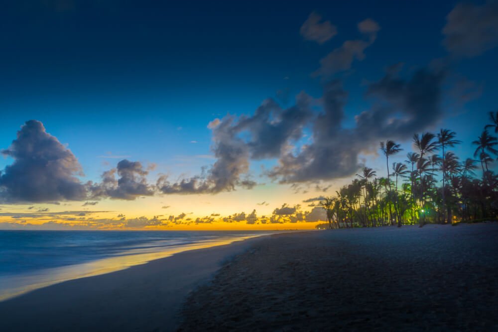 Céu em tons de azul e alaranjado, refletindo suas cores nas águas da praia de Bávaro, em Punta Cana.