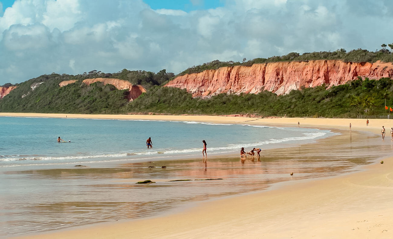 Praia da Pitinga em Arraial d'Ajuda com alguns banhistas na beira do mar.