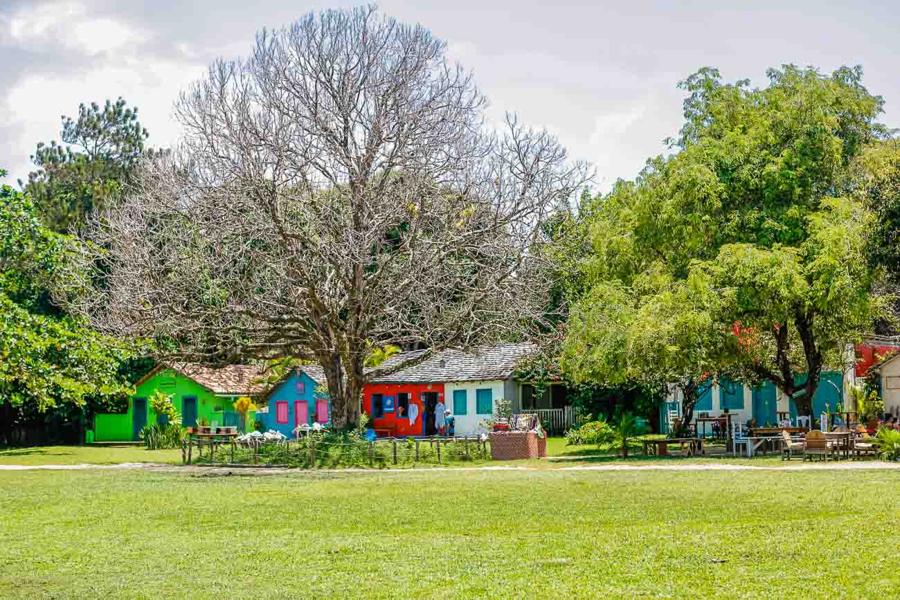 Área gramada e arborizada do Quadrado de Trancoso com casinhas coloridas.