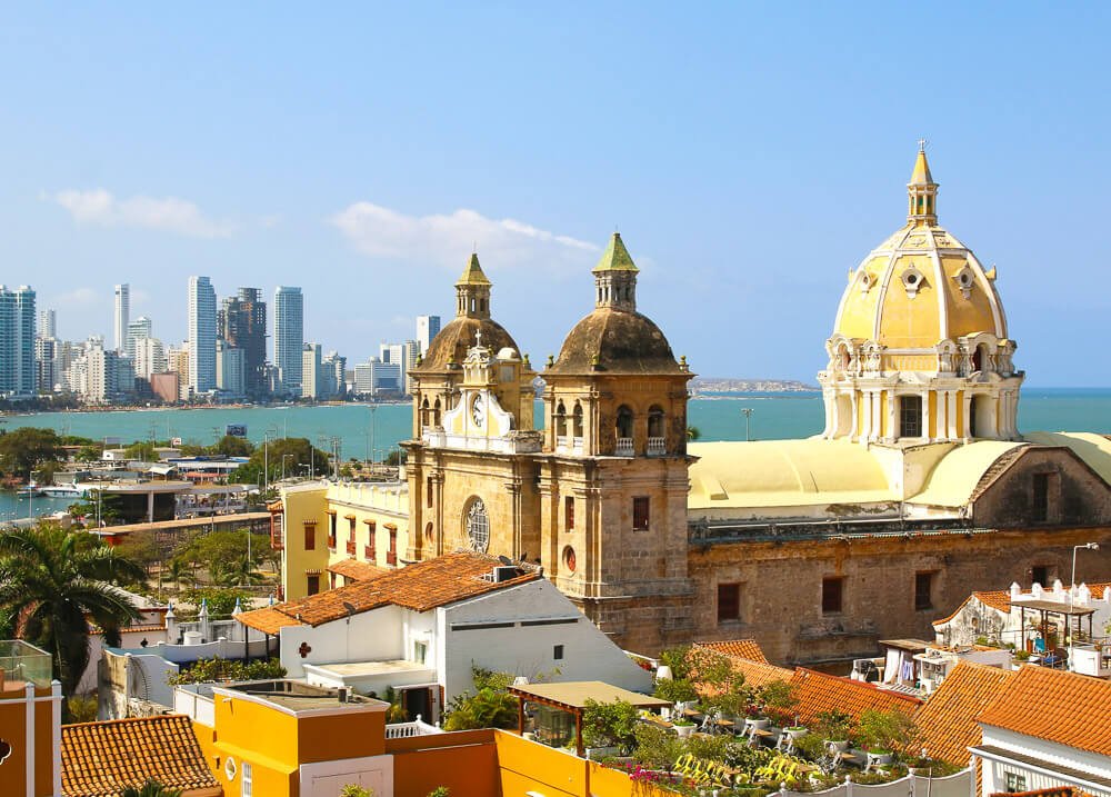 Centro histórico de Cartagena. Há o contraste dos prédios históricos, como a Igreja de São Pedro Claver com o cenário moderno das torres ao fundo.