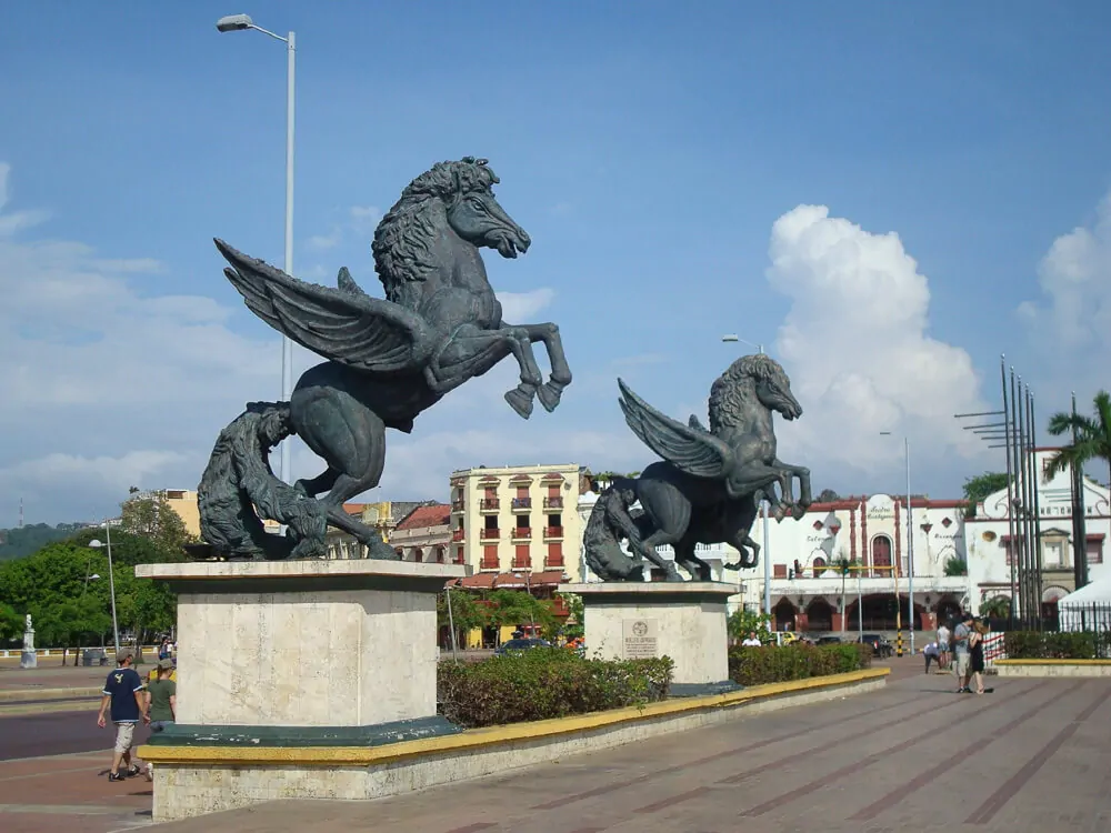 Muelle de Los Pegasos, em Cartagena, com dois grandes pégasos esculpidos. Há turistas caminhando por perto das esculturas.