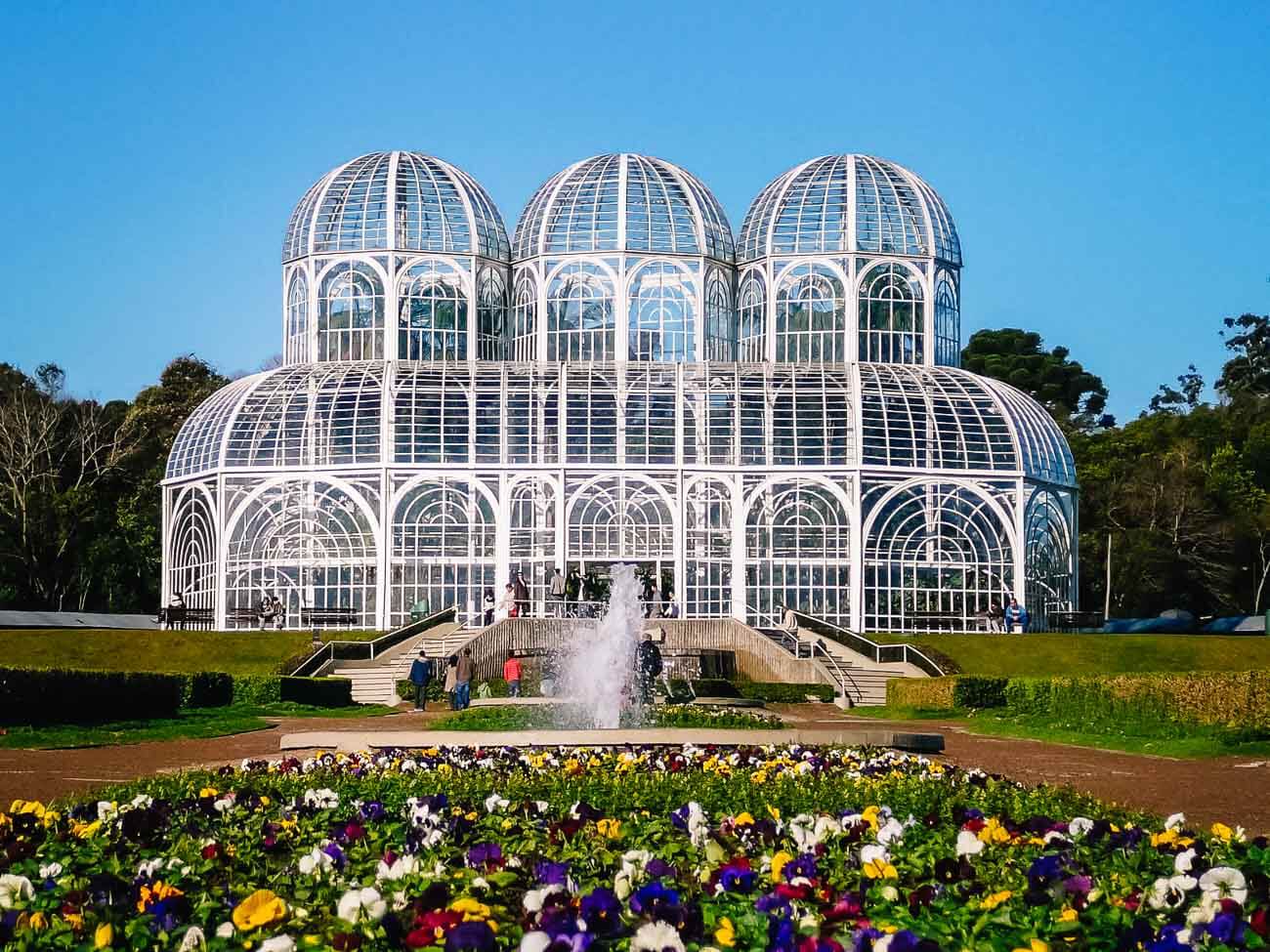 Vista panorâmica da fachada do Jardim Botânico em Curitiba com jardins em volta e na frente.