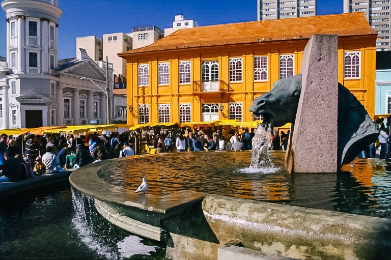 Lago e chafariz no Largo da Ordem em Curitiba durante feira de artesanato.