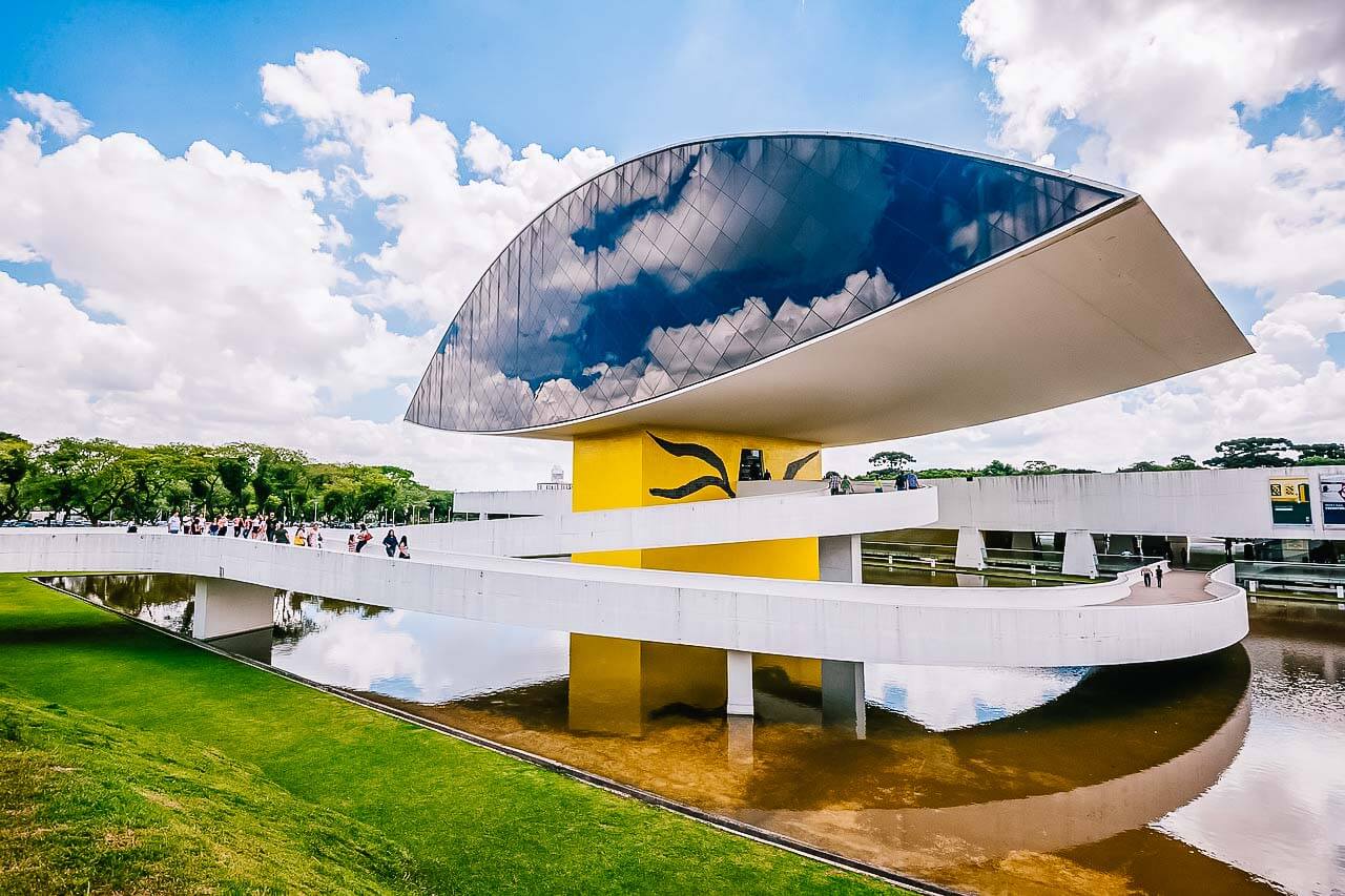 Museu Oscar Niemeyer em Curitiba com construção em formato de um olho ficando sobre um lago.