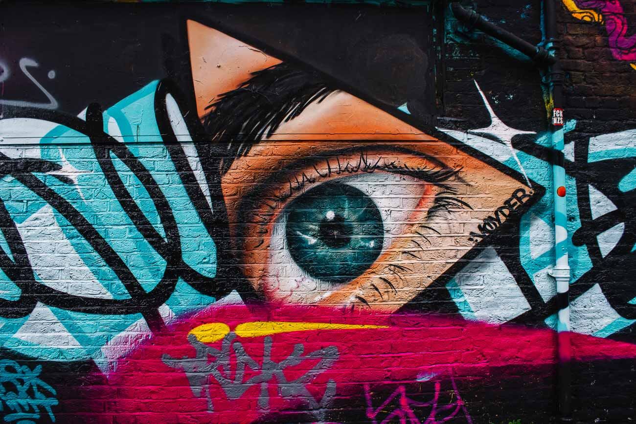 Uma parede pintada de grafite, com o foco em um olho azul.