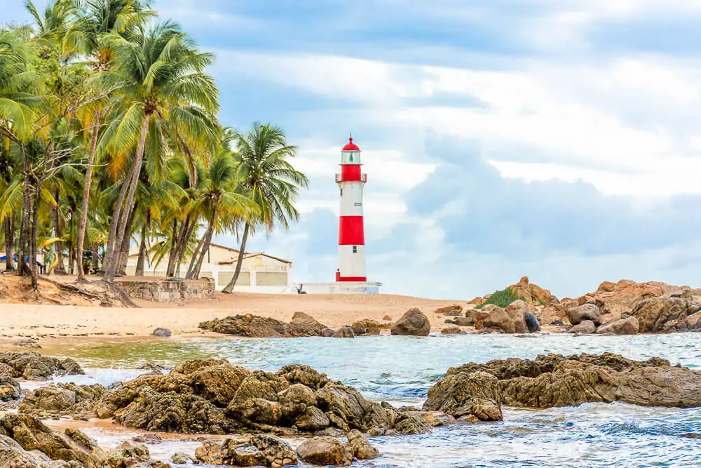 Farol de Itapuã sobre as areias claras da Praia de Itapuã.