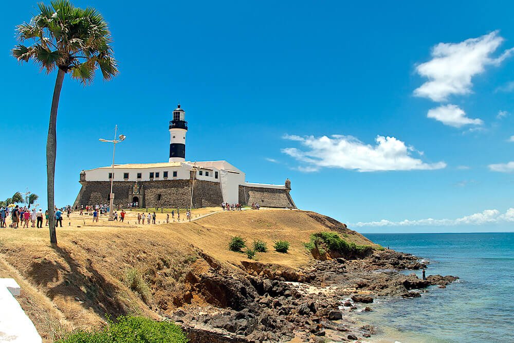 Praia do Farol da Barra com turistas visitando o local.