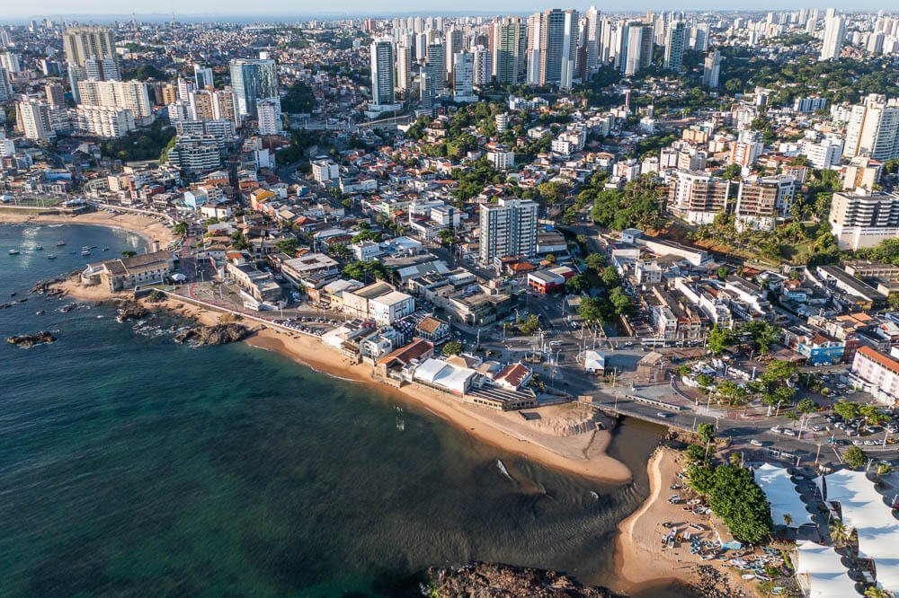 Vista panorâmica para a Praia do Rio Vermelho com mar de águas verdes e muitos prédios à beira-mar.
